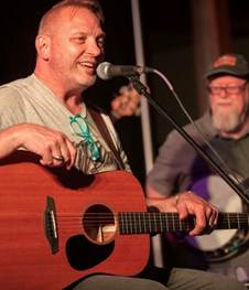 A person holding a guitar and singing into a microphone
AI-generated content may be incorrect.